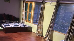 Quarto com cama, mesa de madeira, sofá e vista pela janela grande.