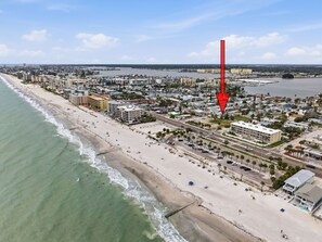 Eine Vogelperspektive einer Küstenstadt mit Strand, Gebäuden und einem Yachthafen.
