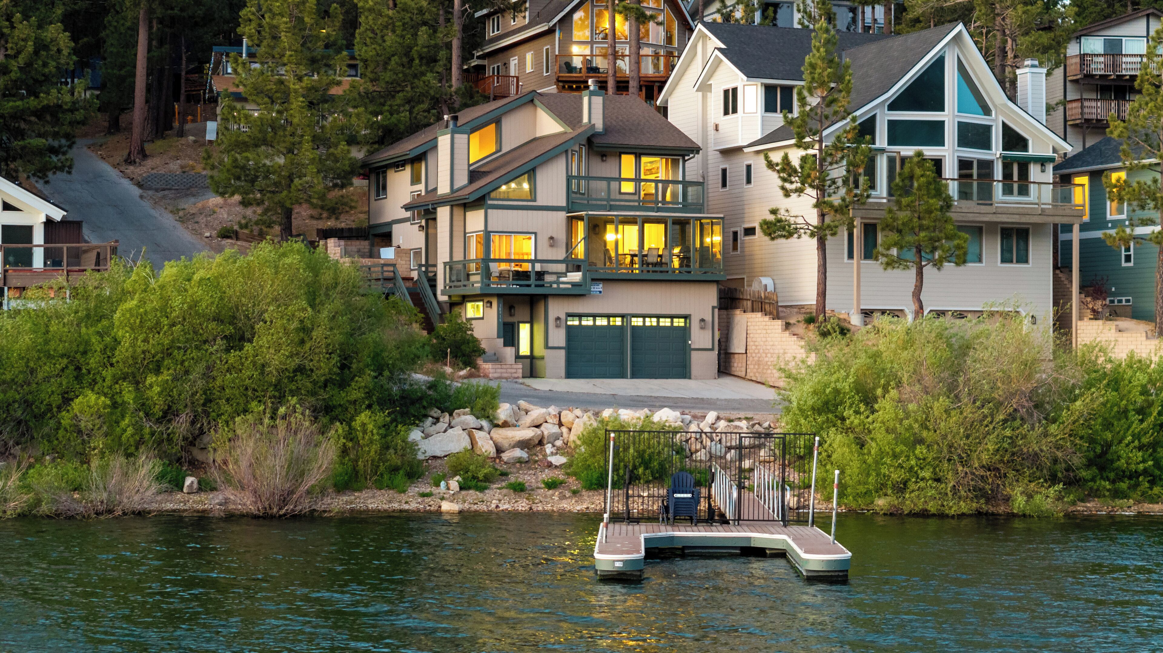 A waterfront property with a dock, multiple-story houses, and a river.