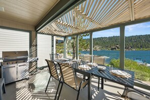 An outdoor dining area with a grill, chairs, and a table set for four. - 5-STAR Lakefront cabin with AMAZING mountain & lake VIEWS! DOCK & GAME ROOM! (Big Bear Lake)