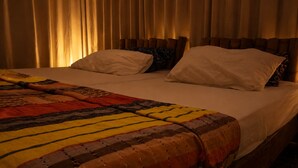 Un lit avec une couverture à motifs, deux oreillers et une tête de lit en bois.