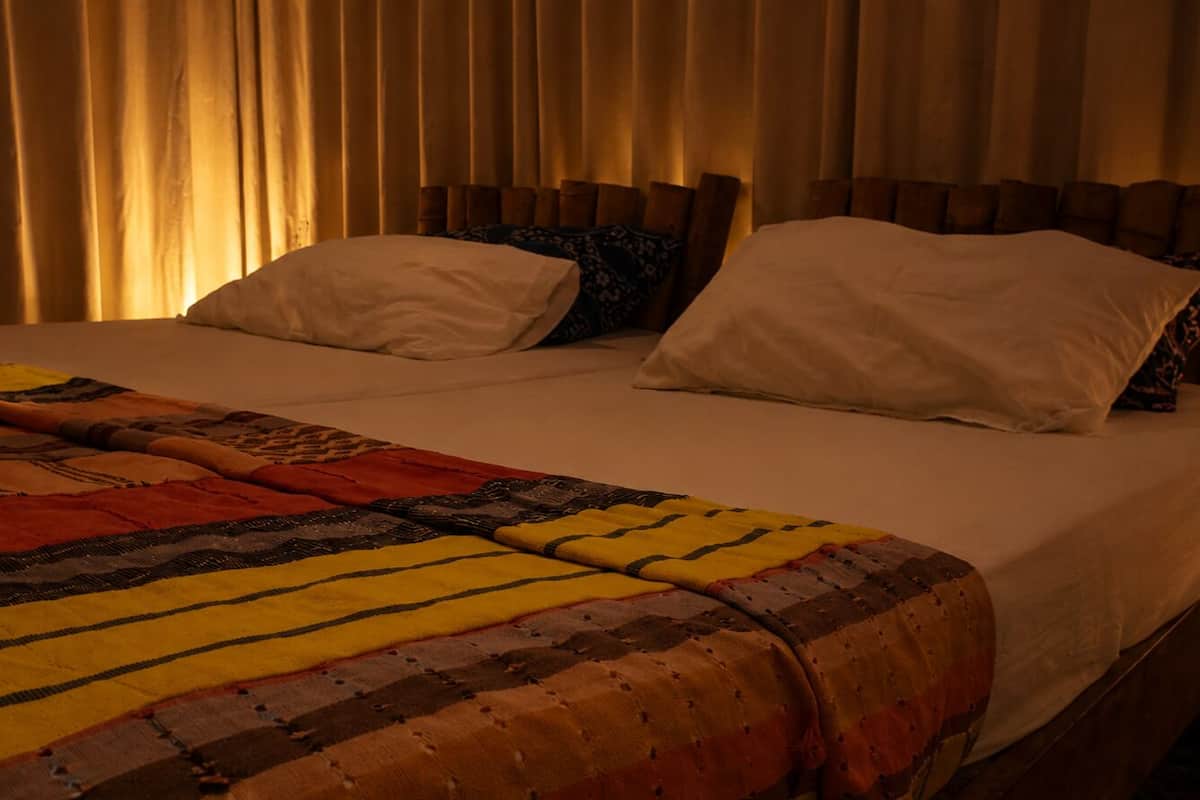 Una cama con un edredón estampado, dos almohadas y cabeceros de madera.