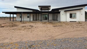 Ett modernt hus i två våningar med en inglasad uteplats, ett garage och en inhägnad trädgård.
