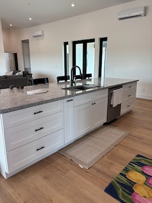 A modern kitchen with white cabinetry, a granite countertop, and a built-in dishwasher. - Enjoyable family friendly 4-bedroom Solar home close to Atessa Podium Club, (Casa Grande)