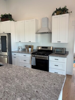 A modern kitchen with white cabinets, a stainless steel refrigerator, a stove, and a microwave. - Enjoyable family friendly 4-bedroom Solar home close to Atessa Podium Club, (Casa Grande)