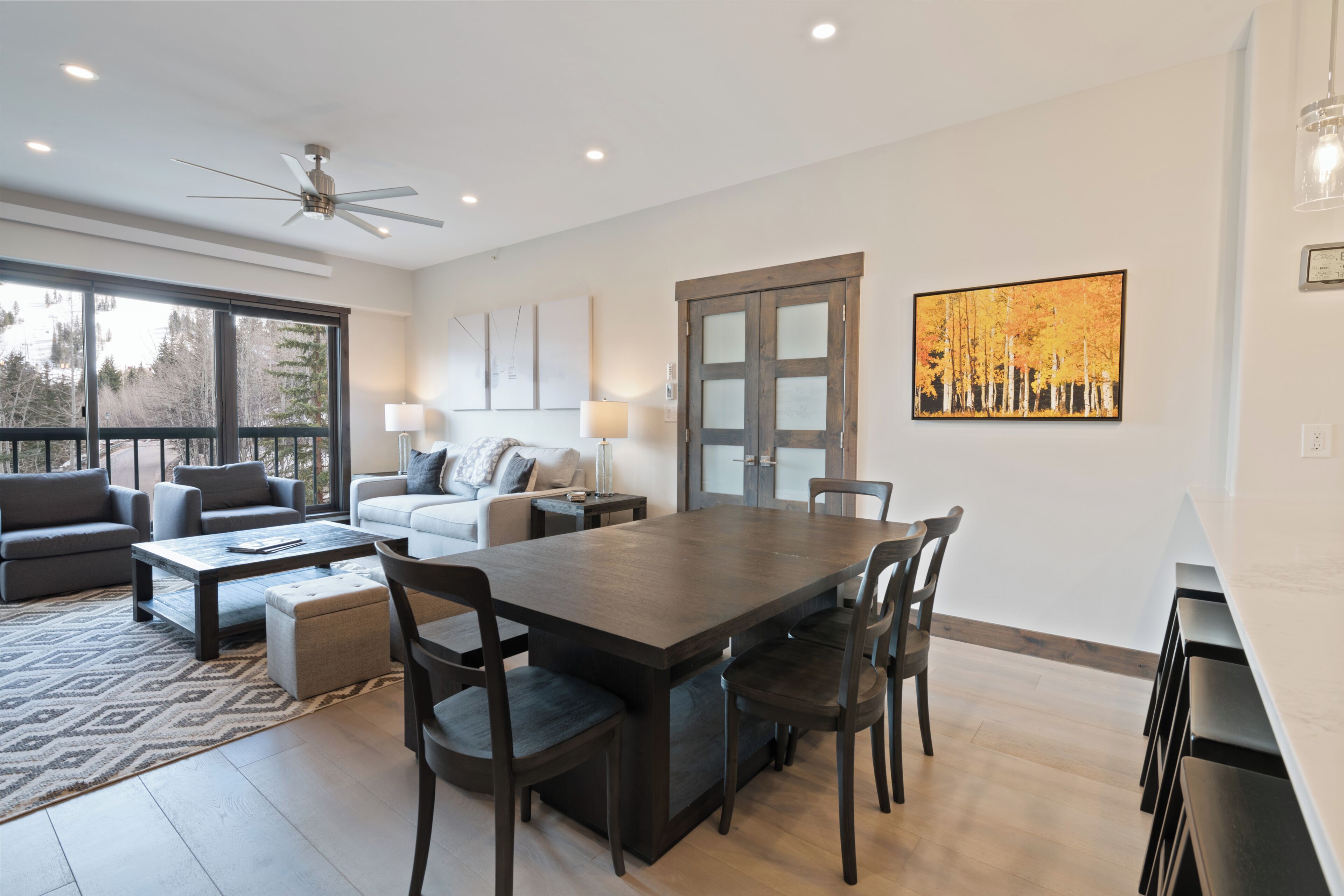 Una sala de estar moderna con una mesa de comedor, sofás y un ventanal grande.