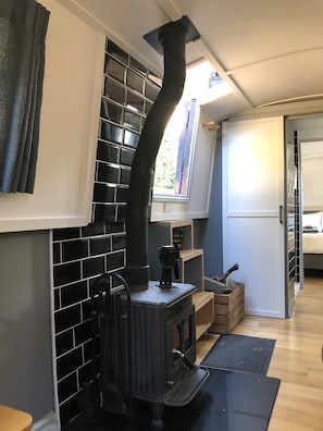 A room with a black tiled stove, a window with a view, and a door leading to another room.