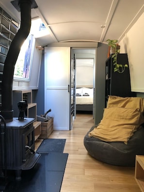 A compact living space with a wood-burning stove, a bed, a bean bag, and a bookshelf.