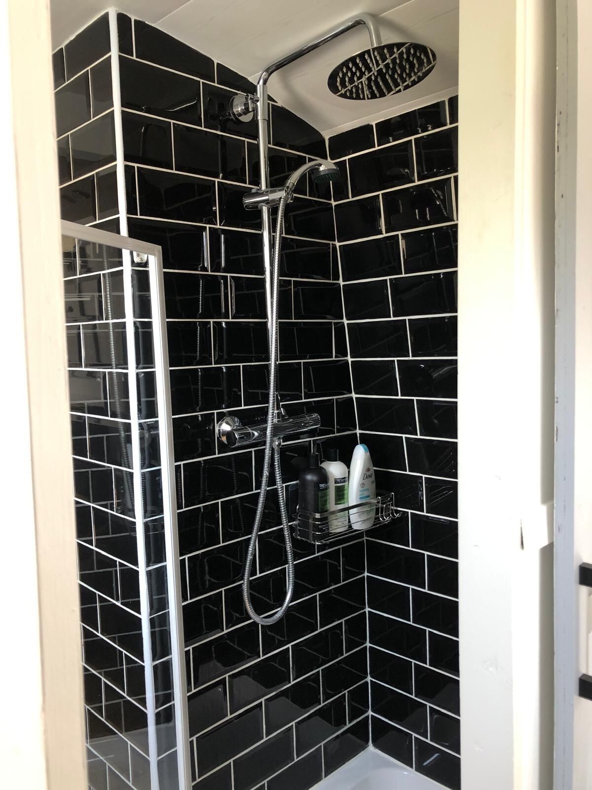 A shower with a handheld showerhead and a wall-mounted rain showerhead.