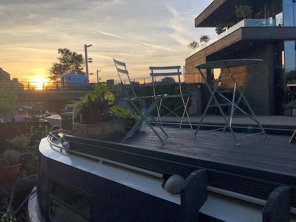 A rooftop terrace with chairs, a table, and potted plants.