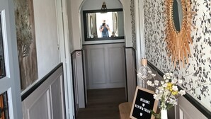 Ein Flur mit freundlicher Begrüßungstafel, einem Spiegel und einer dekorativen Wand.