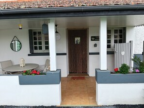 Un espacio al aire libre techado con una mesa, sillas, un farol decorativo y un letrero de bienvenida.