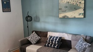 Ein Wohnzimmer mit einer Couch, einem gemusterten Teppich und einem Bild an der Wand.