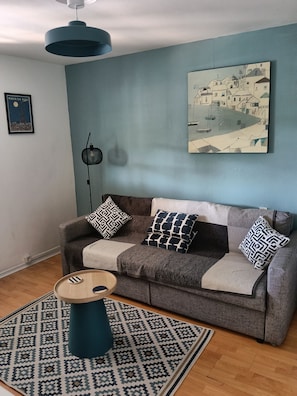 A living room with a sofa, patterned rug, and a painting on the wall. - Perfect 1-bedroom apartment in soothing Vielle-Adour for your stay. (Vielle-Adour)