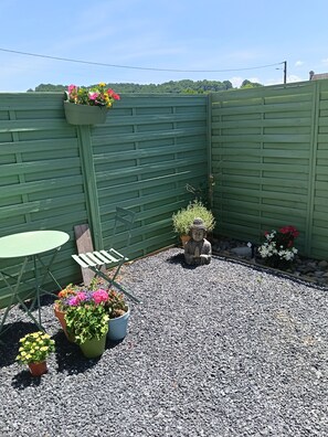 A green wooden fence, a small table, and potted plants in a garden area. - Perfect 1-bedroom apartment in soothing Vielle-Adour for your stay. (Vielle-Adour)