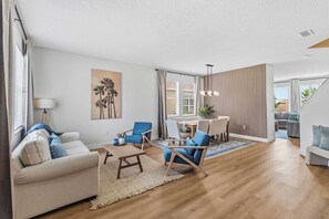 A modern living room with a sofa, chairs, a dining table, and a view of the outdoors. - Theater Room, Game Room & Family Fun near Disney (Davenport)