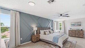 Una camera da letto con un letto, comodini, una cassettiera, una ventola a soffitto e vista sull'esterno.