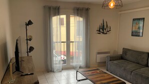 Een woonkamer met een bank, een houten salontafel, een lamp, een gordijn en een schilderij aan de muur.