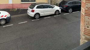 Straatbeeld met gebouwen, geparkeerde auto's en betonnen palen.