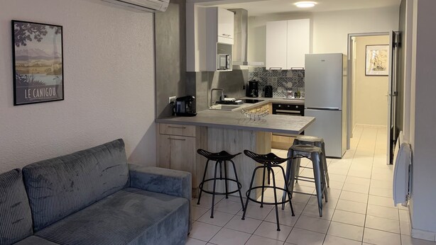Een moderne keuken met een inbouweiland, barstoelen en een eethoek.