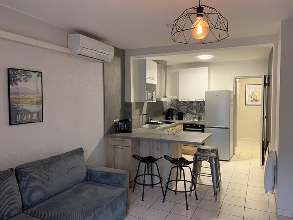 A modern kitchen with a built-in island, bar stools, and a dining area.