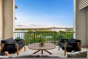 A balcony with two chairs, a table, and a view of a river and cityscape. - Zen Bayline Pool - bay View - Balcony (Darwin)