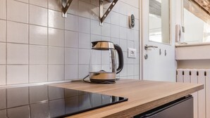 Eine Küche mit modernem Design, mit einer Holzarbeitsplatte, einer schwarzen Induktionskochplatte und einem Edelstahl-Wasserkocher.