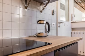Eine Küche mit modernem Design, mit einer Holzarbeitsplatte, einer schwarzen Induktionskochplatte und einem Edelstahl-Wasserkocher.