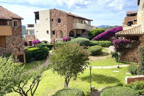 Ein Innenhof mit Steingebäuden, einem Baum und violetten Blumen.