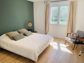 A bedroom with a bed, a chair, a nightstand, a lamp, and a window with curtains. - Large Provencal house (Pujaut)