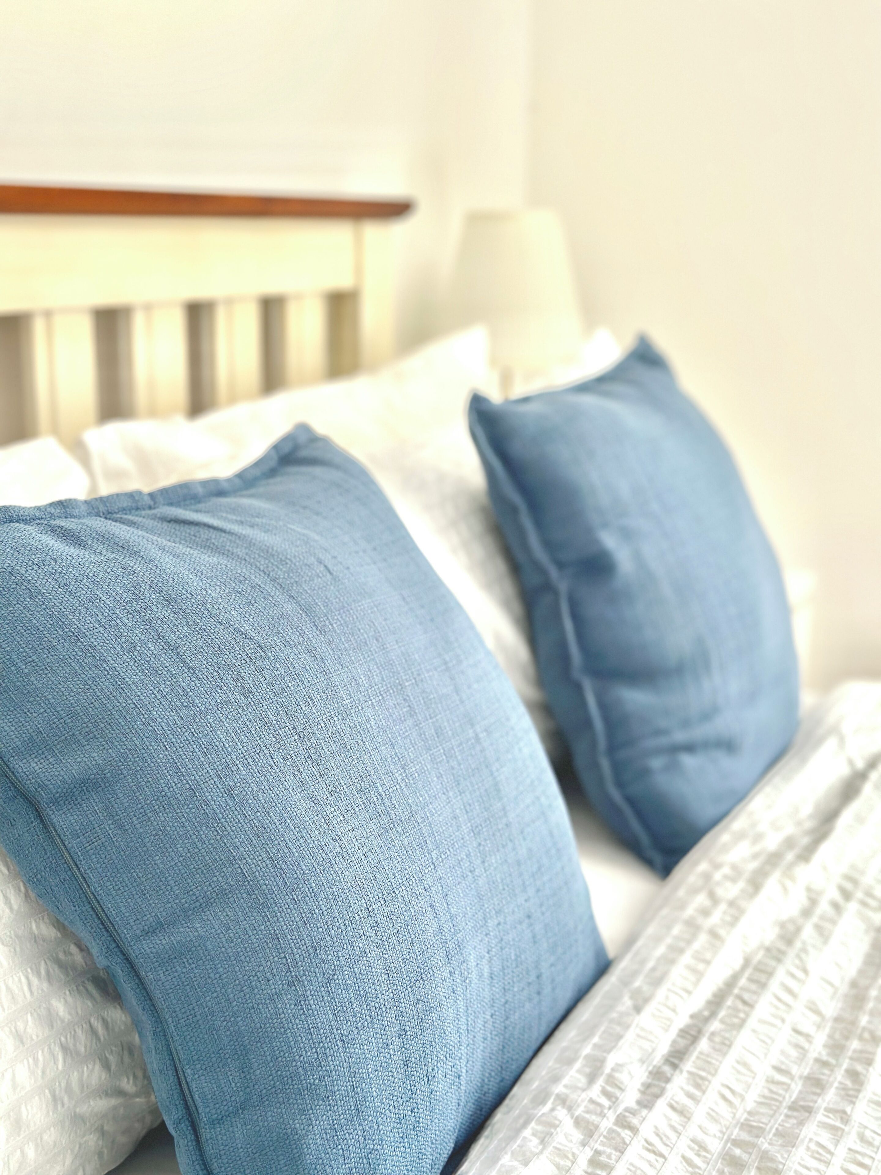 A bed with white and blue pillows, a white headboard, and a patterned bedspread.