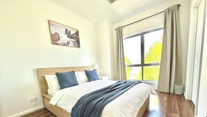 Een slaapkamer met een houten bed, uitzicht op de omgeving en een schilderij aan de muur.