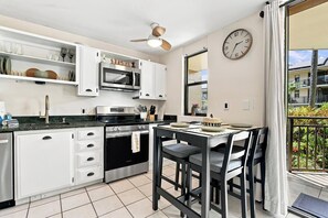 Une cuisine moderne avec des meubles blancs, une cuisinière noire et un coin repas comprenant une table et des chaises.
