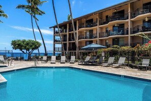 A hotel with a pool, lounge chairs, and a view of the ocean. - Kona Makai 3-105: Ground Floor, Ocean View Beauty (KAILUA KONA)