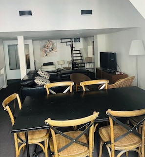 A dining area with a black table and four wooden chairs with woven seats. - Large apartment in the center of CAUTERETS (Cauterets)