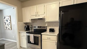 Una cocina con armarios blancos, un refrigerador negro y un horno de acero inoxidable.