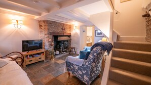 Ein gemütliches Wohnzimmer mit Kamin, Fernseher und einer Treppe.