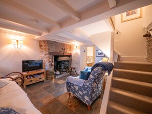 Un salon chaleureux avec une cheminée, un téléviseur et un escalier.