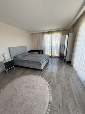 Une chambre moderne avec un grand lit, une armoire, une télévision et une vue sur l’extérieur.