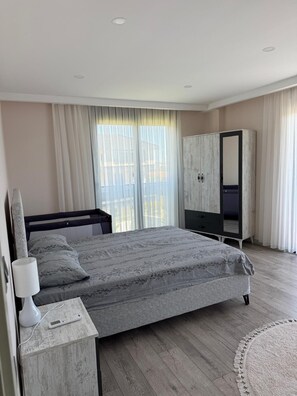 Une chambre à coucher comprenant un lit, une table de chevet, une armoire et une fenêtre avec des rideaux.