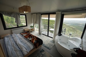 Un dormitorio con una cama grande, una bañera y un balcón con vistas.