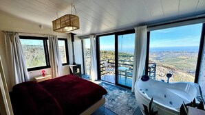 Une chambre avec un grand lit, une baignoire et un balcon avec vue.