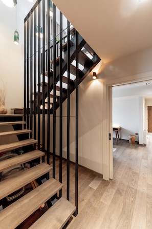 Eine moderne Treppe mit Holzboden und schwarzen Metallgeländern, die zu einer oberen Etage führt.