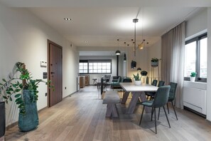 Ein moderner Essbereich mit großem Tisch, Stühlen, Pendelleuchten und Blick durch ein Fenster.
