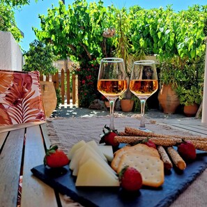 A table with cheese, crackers, and strawberries, two glasses of wine, and a wooden bench with a floral cushion. - Traditional Stone House in a Peaceful Cretan Village - 20' from Heraklion Center (Epano Vatheia)