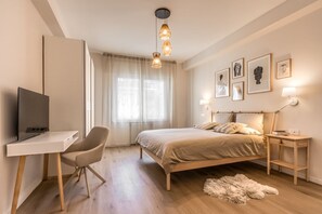 Ein Schlafzimmer mit Bett, Schreibtisch, Stuhl und einem Kunstwerk an der Wand.