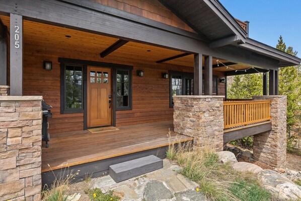 Ein Holzhaus mit Steinuntergrund, einer Holztür und einer Veranda mit Stufen.