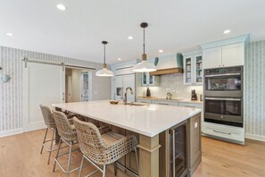 Eine moderne Küche mit einer großen Kochinsel, Edelstahlgeräten und einer Backspüle mit Fischgrätmuster.