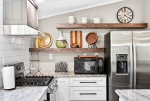 A kitchen with a stainless steel refrigerator, a microwave, a stove, and a coffee maker. - Southern charm at its best (Crossville)