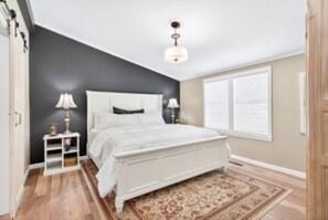 A bedroom with a bed, bedside lamps, a nightstand, a window with blinds, and a ceiling fan. - Southern charm at its best (Crossville)